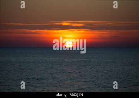 A beautiful sun setting on the horizon on the sea Stock Photo