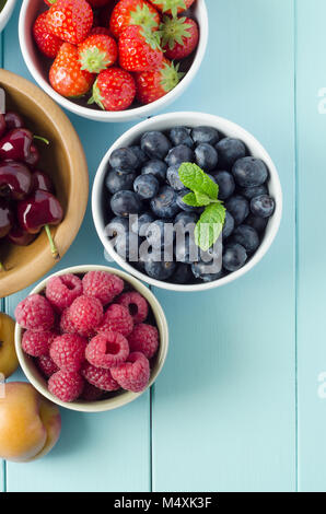Overhead shot of five separated fruit types on light aqua blue painted wood planked table. Stock Photo