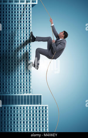 Businessman climbing skyscraper in challenge concept Stock Photo