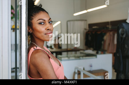 Female fashion designer standing in her boutique. Female dress designer in her cloth shop with designer clothes on display. Stock Photo