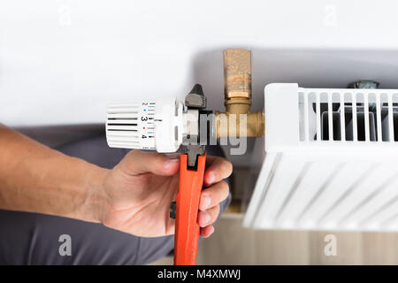 Close-up Of Male Plumber Fixing Thermostat Using Wrench At Home Stock Photo