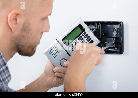 Young Male Technician Installing Security System Using Screwdriver Stock Photo