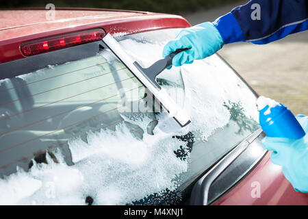 Close-up Of Person's Hand Washing Rear Windshield Of A Car Using Squeegee Stock Photo