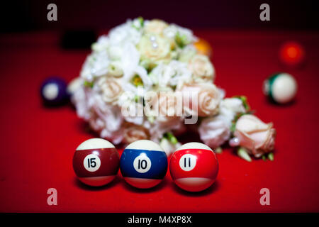 three billiard balls stand in a row on a red table. On the background of flowers Stock Photo