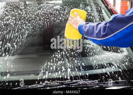 Hand wiping the windshield of a car on a sunny day. Wipe dry with an orange  sponge. Rag wipes water stains on the window Stock Photo - Alamy