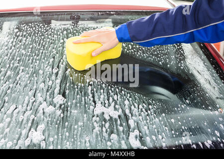 Hand wiping the windshield of a car on a sunny day. Wipe dry with an orange  sponge. Rag wipes water stains on the window Stock Photo - Alamy