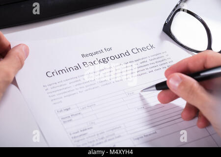 Close-up Of Person Hand Filling Criminal Background Check Application Form Stock Photo