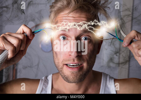 Portrait Of A Man Holding Bared Wires And Screaming Of Pain Stock Photo