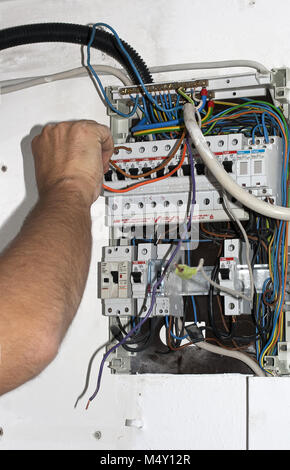 Electrician work connecting cables at switchbox Stock Photo