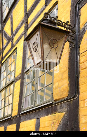 An old metallic lantern hanging from a yellow brick wall in Copenhagen, Denmark Stock Photo