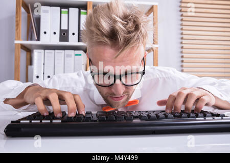 Close-up Of A Concentrating Businessman With Eyeglasses Typing At Keyboard On Desk Stock Photo