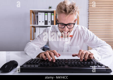 Smiling Young Businessman In Orange Bow Typing On Keyboard In Office Stock Photo