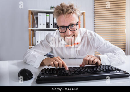 Smiling Young Businessman In Orange Bow Typing On Keyboard In Office Stock Photo