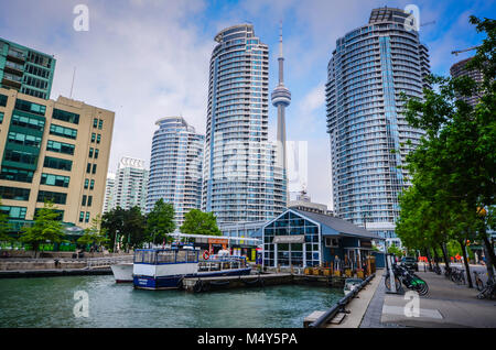 Waterfront scene in Toronto, Canada with boats, ferries, skyscraper, and CN Tower.