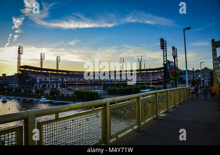 Couples place locks signifying everlasting love on yellow bridge in front of Pittsburgh Pirates PNC Park stadium. Stock Photo