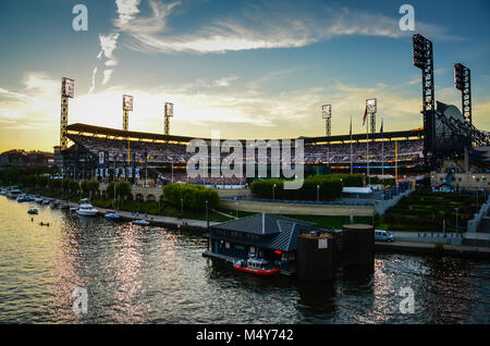 Pittsburgh, PA, USA. Lights on at twilight at Pittsburgh Pirates PNC Park arena with stadium seats filled by spectators watching a baseball game. Stock Photo