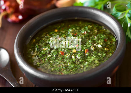 Raw homemade Argentinian green Chimichurri or Chimmichurri salsa or sauce made of parsley, garlic, oregano, hot pepper, olive oil, vinegar Stock Photo