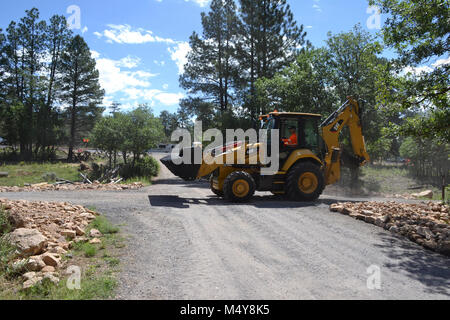A front loader carries asphalt to where the trail is being paved.  Between August 10 to September 10, 2016 the Greenway Trail between the IMAX Theater parking area in Tusayan and Center Road in Grand Canyon National Park will be closed while Grand Canyon's trail crew installs asphalt. The portion of the trail north of Center Road will not be affected.  While the trail closure is in effect, cyclists and hikers may ride the Tusayan shuttle (Purple Route) which is equipped with bicycle carrier racks. The shuttle connects Tusayan with the South Rim Visitor Center, a 20 minute ride each way.  The i Stock Photo