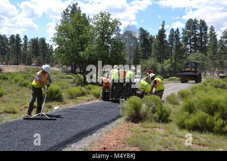 Smoothing of asphalt continues as another load comes.  Between August 10 to September 10, 2016 the Greenway Trail between the IMAX Theater parking area in Tusayan and Center Road in Grand Canyon National Park will be closed while Grand Canyon's trail crew installs asphalt. The portion of the trail north of Center Road will not be affected.  While the trail closure is in effect, cyclists and hikers may ride the Tusayan shuttle (Purple Route) which is equipped with bicycle carrier racks. The shuttle connects Tusayan with the South Rim Visitor Center, a 20 minute ride each way.  The intent of thi Stock Photo