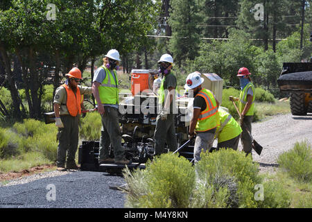 Workers look back at their progress.  Between August 10 to September 10, 2016 the Greenway Trail between the IMAX Theater parking area in Tusayan and Center Road in Grand Canyon National Park will be closed while Grand Canyon's trail crew installs asphalt. The portion of the trail north of Center Road will not be affected.  While the trail closure is in effect, cyclists and hikers may ride the Tusayan shuttle (Purple Route) which is equipped with bicycle carrier racks. The shuttle connects Tusayan with the South Rim Visitor Center, a 20 minute ride each way.  The intent of this project is to c Stock Photo