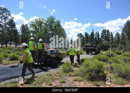 A load of asphalt comes while workers continue to smooth out the Greenway Trail.  Between August 10 to September 10, 2016 the Greenway Trail between the IMAX Theater parking area in Tusayan and Center Road in Grand Canyon National Park will be closed while Grand Canyon's trail crew installs asphalt. The portion of the trail north of Center Road will not be affected.  While the trail closure is in effect, cyclists and hikers may ride the Tusayan shuttle (Purple Route) which is equipped with bicycle carrier racks. The shuttle connects Tusayan with the South Rim Visitor Center, a 20 minute ride e Stock Photo