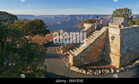 The stone memorial at Powell Point (along historic Hermit Road on the South Rim) commemorates the 1869 and 1871-72 exploratory river trips through Grand Canyon on the Colorado River by Major John Wesley Powell and his crew members. Stunning 200° vistas, can be enjoyed from Powell Point.  Download our 2018 Trip Planner:   two people are climbing the stone steps of the Powell Memorial monument, a masonry structure that is about 20 ft square and 20 feet tall, with an observation desk and a large bronze commemorative plaque on the upper level. The monument is on the edge of the canyon and in the b Stock Photo