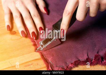A close-up of a young furrier woman sew natural fur for making a woman's fur coat. The process of making a woman's fur coat Stock Photo