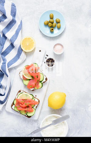 Sandwiches with salmon, cucumber and cream cheese on white background. Top view. Mediterranean cuisine Stock Photo