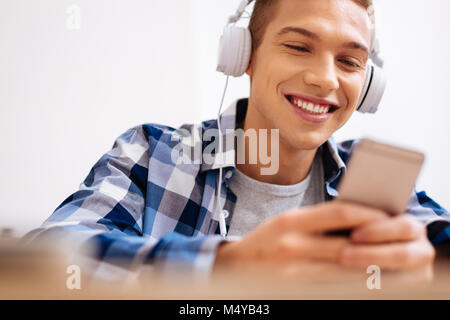 Joyful boy wearing headphones and using his phone Stock Photo