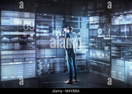 Serious programmer looking thoughtful while standing in front of the screen Stock Photo
