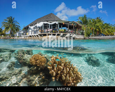 Restaurant on the sea shore with coral and fish underwater, split view above and below surface, Rangiroa, Tuamotus, Pacific ocean, French Polynesia Stock Photo