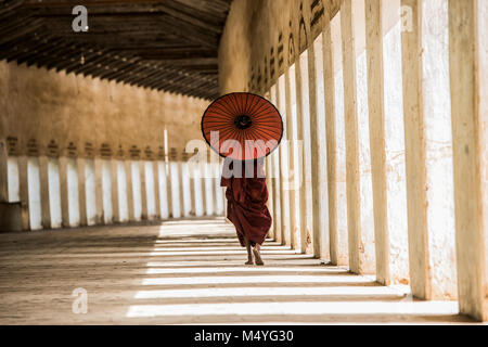 monk with red traditional costumes and red umbrella in Buddhist giant temple Stock Photo