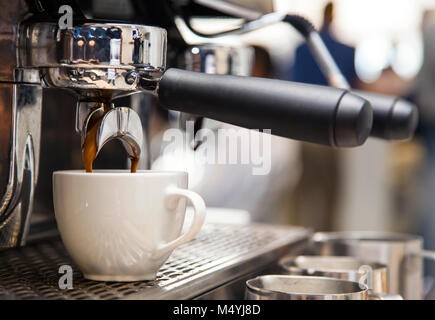 Close up of coffee going into cup from barista machine in coffee shop. Americano being made. Stock Photo