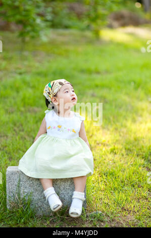 Little baby sitting on the lawn watching the sky Stone Stock Photo