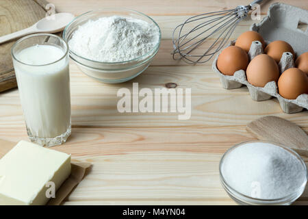 Ingredients for baking dough. Flour, eggs, butter, milk and sugar on the kitchen table. Stock Photo