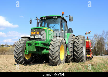 SALO, FINLAND – MAY 11, 2013: John Deere 6620 agricultural tractor and cultivator on field in Salo, Finland on May 11. On June 28, John Deere announce Stock Photo