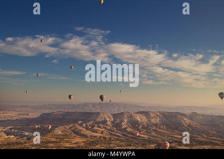 Hot air balloons flying above mountains at sunset, Cappadocia, Turkey Stock Photo