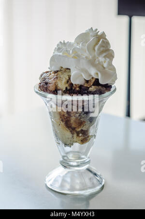 Layers of blueberry cobbler topped with fresh whipped cream in a parlor ice cream glass. Stock Photo