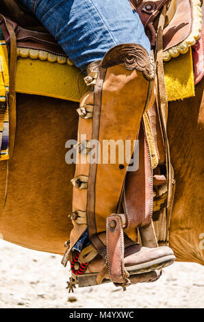 Hand-tooled leather coverings of leg worn by a charro, a traditional Mexican cowboy, astride a horse. Stock Photo