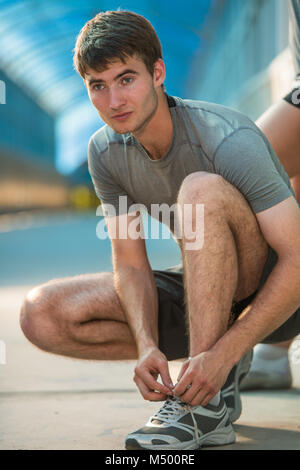 Handsome man lacing his shoes before running outdoors Stock Photo
