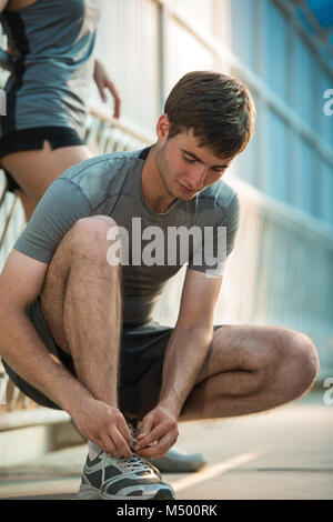 Handsome man lacing his shoes before running outdoors Stock Photo