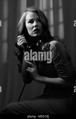 Film Noir style image of woman with long hair on telephone Stock Photo