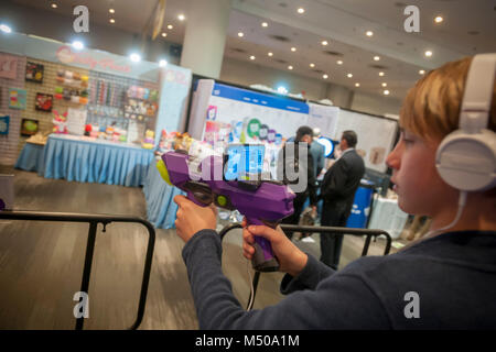 New York, USA. 19th February, 2018. A presenter demonstrates the Merge 6DoF (6 Degrees of Freedom) Blaster at the 115th North American International Toy Fair in the Jacob Javits Convention center in New York on Monday, February 19, 2018.  An accessible virtual reality product using your smartphone. (© Richard B. Levine) Credit: Richard Levine/Alamy Live News Stock Photo