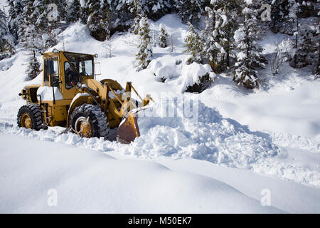 Noxon, Montana, USA. 19th February, 2018. Snow event. A Caterpillar 950 rubber tired articulated loader clearing snow on a mountain road north of Noxon, in Sanders County Montana. The loader is operated by Delbert Bowe of Libby, Montana. The road is located in a remote section of the Cabinet Mountains, about 20 miles north of Noxon, Montana. The area was hit with heavy snow that came in from the west over the weekend, that lasted several days and dumped over 20 inches of snow in the higher elevations. Stock Photo