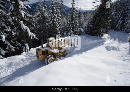 Noxon, Montana, USA. 19th February, 2018. Snow event. A Caterpillar 950 rubber tired articulated loader clearing snow on a mountain road north of Noxon, in Sanders County Montana. The loader is operated by Delbert Bowe of Libby, Montana. The road is located in a remote section of the Cabinet Mountains, about 20 miles north of Noxon, Montana. The area was hit with heavy snow that came in from the west over the weekend, that lasted several days and dumped over 20 inches of snow in the higher elevations. Stock Photo