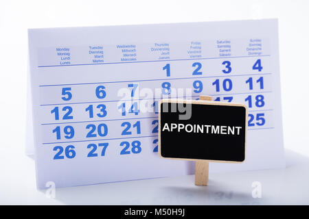 Miniature Appointment Placard In Front Of Calendar Against White Background Stock Photo