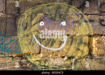 A crudely painted smiley on a sandstone wall. Stock Photo