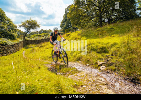 Female mountain biker on trail near Winster in the English Lake District Stock Photo