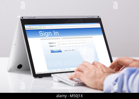 Close-up Of Businessman Using Digital Tablet For Signing In Over The White Desk At Workplace Stock Photo