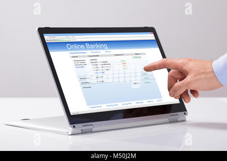 Close-up Of Male's Hand Using Online Banking On Hybrid Laptop Over The White Desk Stock Photo